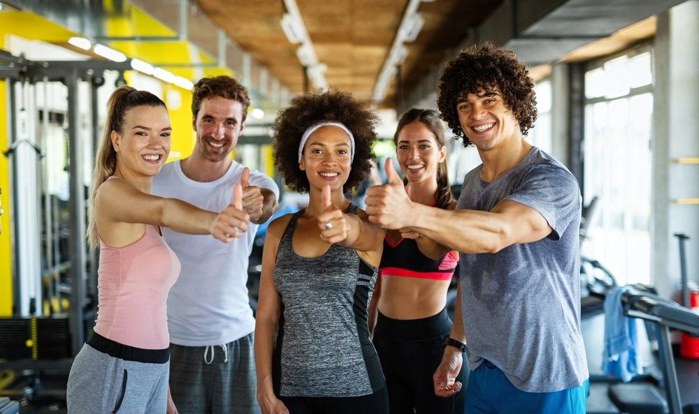 Gruppe Fitness Gruppe junger Menschen halten ihre Daumen hoch